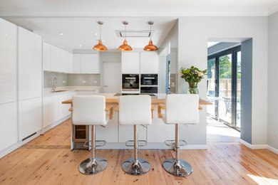 Photo of a large contemporary u-shaped open plan kitchen in Other with bamboo flooring and an island.