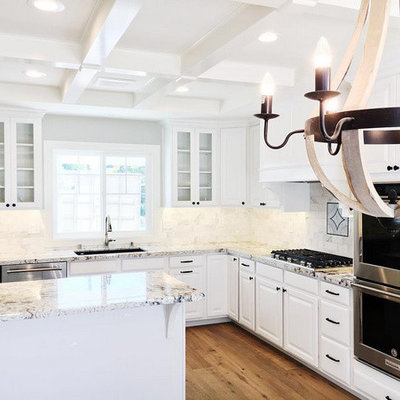 Example of a mid-sized arts and crafts u-shaped light wood floor and brown floor eat-in kitchen design in Los Angeles with an undermount sink, raised-panel cabinets, white cabinets, granite countertops, white backsplash, stone tile backsplash, stainless steel appliances and an island