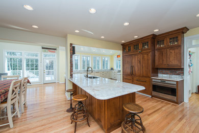 Open concept kitchen - huge traditional light wood floor open concept kitchen idea in DC Metro with an undermount sink, raised-panel cabinets, white cabinets, quartzite countertops, white backsplash, stone slab backsplash, stainless steel appliances and an island