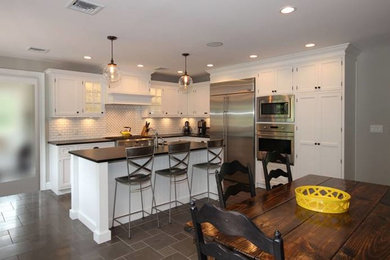 Large transitional l-shaped porcelain tile eat-in kitchen photo in New York with a drop-in sink, beaded inset cabinets, white cabinets, granite countertops, white backsplash, ceramic backsplash, stainless steel appliances and an island