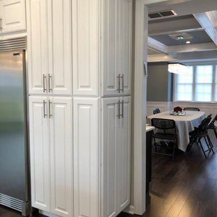 Ispirazione per una grande cucina ad U tradizionale con lavello sottopiano, ante con bugna sagomata, ante bianche, top in quarzite, paraspruzzi grigio, paraspruzzi con piastrelle in ceramica, elettrodomestici in acciaio inossidabile, pavimento in laminato, isola, pavimento marrone e top giallo