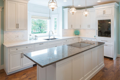 Large classic u-shaped kitchen/diner in Cincinnati with a double-bowl sink, flat-panel cabinets, white cabinets, granite worktops, white splashback, ceramic splashback, medium hardwood flooring, an island and stainless steel appliances.