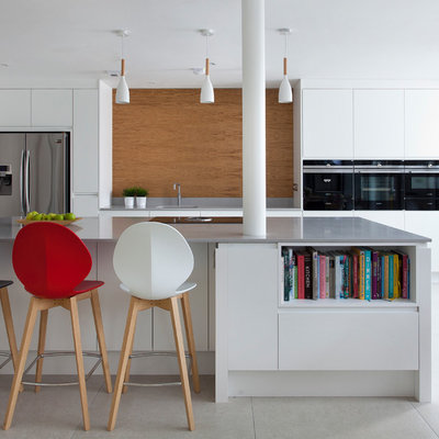 Example of a trendy galley gray floor open concept kitchen design in Other with an undermount sink, flat-panel cabinets, white cabinets, brown backsplash, stainless steel appliances, an island and gray countertops