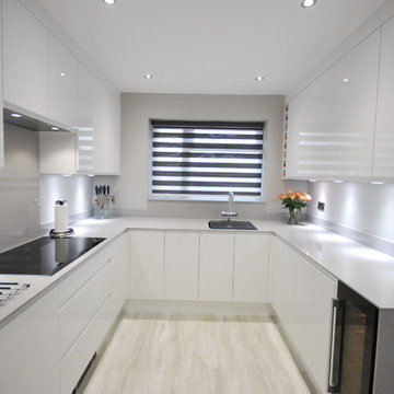 White gloss j-pull contemporary kitchen with light grey quartz worktop.