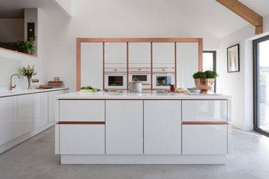 Inspiration for a contemporary u-shaped open plan kitchen in Other with a submerged sink, flat-panel cabinets, white cabinets, white splashback, integrated appliances, concrete flooring, an island, grey floors and white worktops.