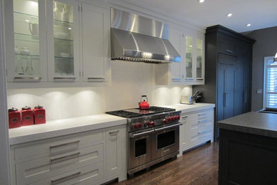 Example of a transitional single-wall light wood floor eat-in kitchen design in Toronto with shaker cabinets, white cabinets, quartz countertops, white backsplash, stone tile backsplash, stainless steel appliances and an island