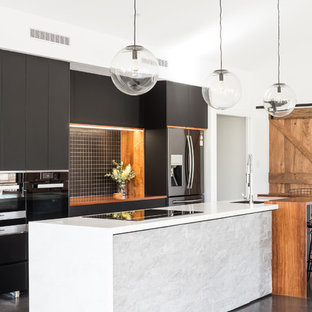 Inspiration for a mid-sized contemporary galley open plan kitchen in Hobart with an undermount sink, black cabinets, solid surface benchtops, black splashback, ceramic splashback, stainless steel appliances, concrete floors, with island, grey floor, white benchtop and flat-panel cabinets.