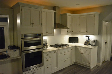 ボストンにある低価格の中くらいなトラディショナルスタイルのおしゃれなキッチン (エプロンフロントシンク、インセット扉のキャビネット、白いキャビネット、シルバーの調理設備、珪岩カウンター、磁器タイルの床、白いキッチンカウンター) の写真