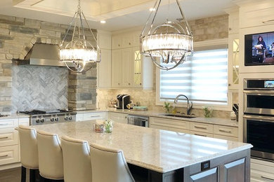 Inspiration for a large timeless l-shaped porcelain tile and brown floor eat-in kitchen remodel in Other with a double-bowl sink, white cabinets, quartz countertops, porcelain backsplash, stainless steel appliances, an island, white countertops, raised-panel cabinets and gray backsplash