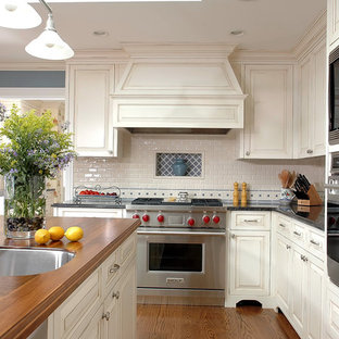 Mid-sized traditional kitchen designs - Mid-sized elegant kitchen photo in Chicago with stainless steel appliances, wood countertops, an undermount sink, raised-panel cabinets, white backsplash and subway tile backsplash