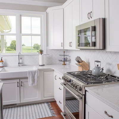 Inspiration for a mid-sized transitional l-shaped medium tone wood floor and brown floor open concept kitchen remodel in Other with a farmhouse sink, shaker cabinets, white cabinets, white backsplash, paneled appliances, an island, quartzite countertops and subway tile backsplash
