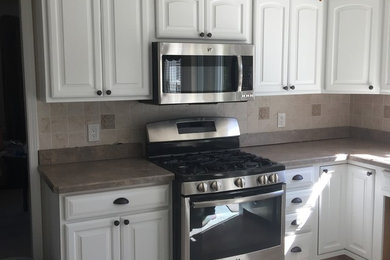 クリーブランドにあるコンテンポラリースタイルのおしゃれなキッチン (白いキャビネット、シルバーの調理設備) の写真