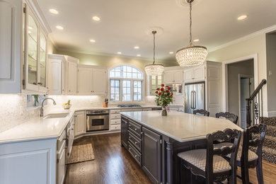 Example of a large classic u-shaped dark wood floor and brown floor eat-in kitchen design in Kansas City with an undermount sink, raised-panel cabinets, white cabinets, marble countertops, white backsplash, mosaic tile backsplash, stainless steel appliances and an island