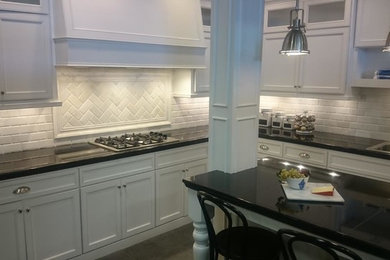 Example of a mid-sized transitional l-shaped eat-in kitchen design in Baltimore with a double-bowl sink, recessed-panel cabinets, white cabinets, quartz countertops, white backsplash, ceramic backsplash, stainless steel appliances and an island