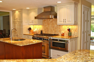 Foto på ett stort vintage kök, med en undermonterad diskho, luckor med upphöjd panel, vita skåp, granitbänkskiva, beige stänkskydd, stänkskydd i keramik, rostfria vitvaror, mellanmörkt trägolv och en köksö