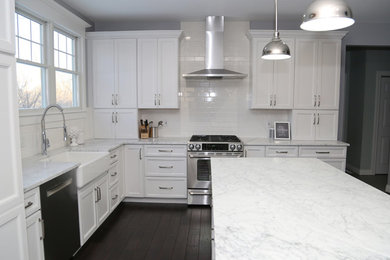 Example of a large transitional l-shaped dark wood floor eat-in kitchen design in Chicago with recessed-panel cabinets, stainless steel appliances, an island, a farmhouse sink, white cabinets, quartz countertops, white backsplash and subway tile backsplash