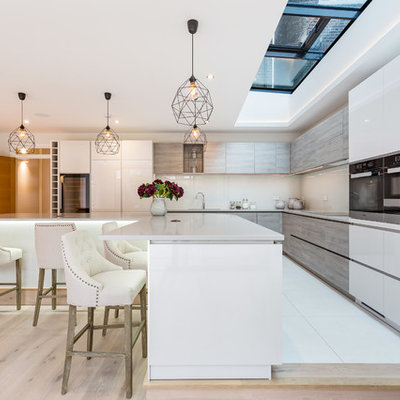 Large trendy ceramic tile and white floor kitchen photo in London with a drop-in sink, flat-panel cabinets, white cabinets, quartz countertops, beige backsplash, ceramic backsplash and an island