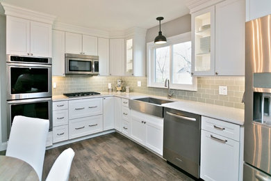 Inspiration for a timeless vinyl floor kitchen remodel in St Louis with a farmhouse sink, shaker cabinets, white cabinets, quartz countertops, gray backsplash and glass tile backsplash