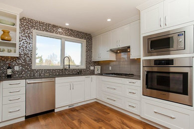 Example of a transitional u-shaped enclosed kitchen design in Edmonton with an undermount sink, shaker cabinets, white cabinets, concrete countertops, multicolored backsplash, mosaic tile backsplash, stainless steel appliances and no island