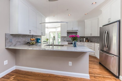 Eat-in kitchen - transitional medium tone wood floor eat-in kitchen idea in DC Metro with a single-bowl sink, shaker cabinets, white cabinets, granite countertops, gray backsplash, stainless steel appliances, a peninsula and stone tile backsplash