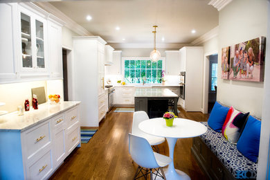 Mid-sized transitional l-shaped medium tone wood floor eat-in kitchen photo in Other with a farmhouse sink, recessed-panel cabinets, white cabinets, marble countertops, white backsplash, stainless steel appliances and an island