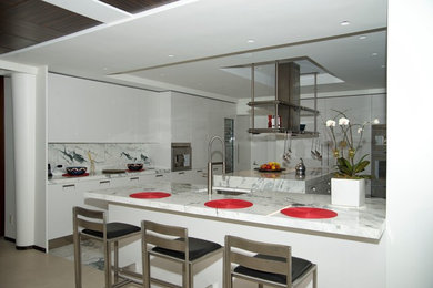 Enclosed kitchen - large modern u-shaped enclosed kitchen idea in New York with an undermount sink, flat-panel cabinets, white cabinets, quartz countertops, multicolored backsplash, stone slab backsplash, stainless steel appliances and an island
