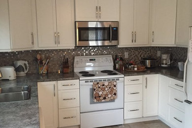 Eat-in kitchen - mid-sized traditional u-shaped travertine floor eat-in kitchen idea in Calgary with a double-bowl sink, shaker cabinets, white cabinets, multicolored backsplash, mosaic tile backsplash, white appliances and no island