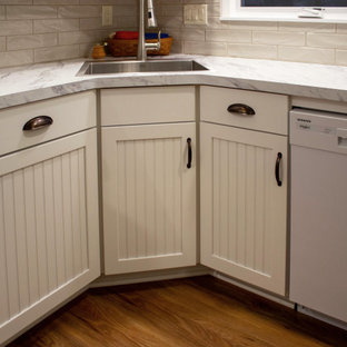 Photo of a small transitional l-shaped eat-in kitchen in Cleveland with an undermount sink, recessed-panel cabinets, white cabinets, laminate benchtops, beige splashback, porcelain splashback, white appliances, vinyl floors, no island, brown floor and white benchtop.