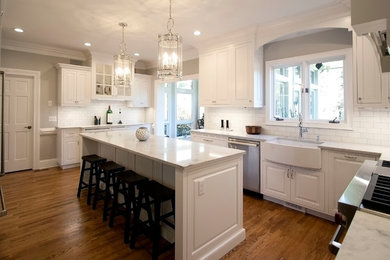 Enclosed kitchen - mid-sized transitional l-shaped light wood floor enclosed kitchen idea in Charlotte with a farmhouse sink, beaded inset cabinets, white cabinets, marble countertops, white backsplash, ceramic backsplash, stainless steel appliances and an island