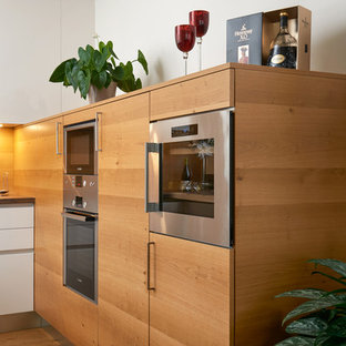 Aménagement d'une cuisine contemporaine en U de taille moyenne avec un évier posé, un placard à porte plane, des portes de placard blanches, un plan de travail en stratifié, une crédence marron, une crédence en bois, un électroménager en acier inoxydable, un sol en contreplaqué et aucun îlot.
