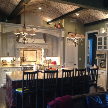 White kitchen with port-red island and scalloped brick ceiling