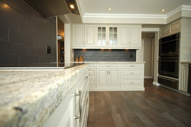 Mid-sized trendy l-shaped eat-in kitchen photo in Toronto with an undermount sink, raised-panel cabinets, white cabinets, granite countertops, gray backsplash, stainless steel appliances, an island and ceramic backsplash