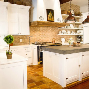 This is an example of a mid-sized country u-shaped eat-in kitchen in New York with a double-bowl sink, shaker cabinets, white cabinets, solid surface benchtops, multi-coloured splashback, brick splashback, stainless steel appliances, ceramic floors and with island.