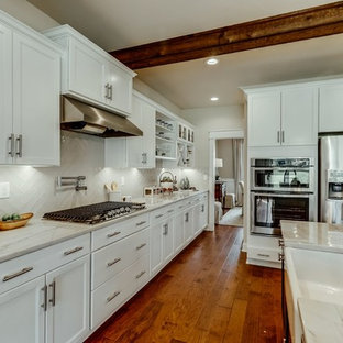 Mid-sized contemporary open concept kitchen remodeling - Example of a mid-sized trendy l-shaped medium tone wood floor and brown floor open concept kitchen design in Richmond with a farmhouse sink, shaker cabinets, white cabinets, quartzite countertops, white backsplash, subway tile backsplash, stainless steel appliances and an island