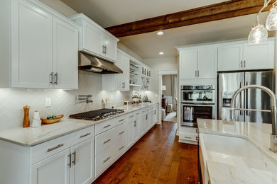 Example of a mid-sized trendy l-shaped medium tone wood floor and brown floor open concept kitchen design in Richmond with a farmhouse sink, shaker cabinets, white cabinets, quartzite countertops, white backsplash, subway tile backsplash, stainless steel appliances and an island