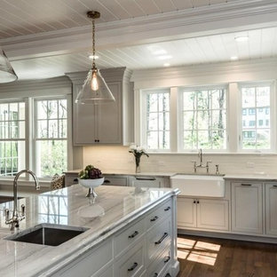 Farmhouse kitchen pictures - Cottage medium tone wood floor kitchen photo in Boston with a farmhouse sink, raised-panel cabinets, gray cabinets, quartzite countertops, white backsplash, porcelain backsplash, stainless steel appliances and an island