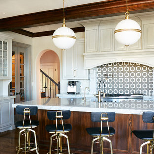 Large transitional open concept kitchen pictures - Open concept kitchen - large transitional medium tone wood floor and brown floor open concept kitchen idea in Other with a farmhouse sink, raised-panel cabinets, white cabinets, quartzite countertops, gray backsplash, mosaic tile backsplash, stainless steel appliances, an island and white countertops
