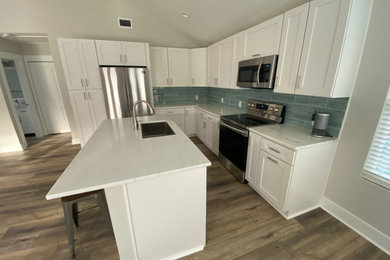 Example of a mid-sized beach style single-wall eat-in kitchen design in Jacksonville with a single-bowl sink, shaker cabinets, white cabinets, blue backsplash, stainless steel appliances, an island, white countertops and marble countertops
