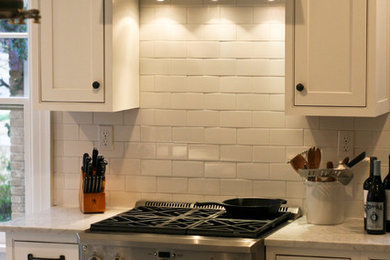Eat-in kitchen - mid-sized country galley ceramic tile eat-in kitchen idea in Oklahoma City with a farmhouse sink, flat-panel cabinets, white cabinets, marble countertops, white backsplash, subway tile backsplash, stainless steel appliances, an island and gray countertops