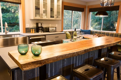 Design ideas for a medium sized rustic galley open plan kitchen in Seattle with a belfast sink, raised-panel cabinets, black cabinets, composite countertops, stainless steel appliances, porcelain flooring, an island and grey floors.