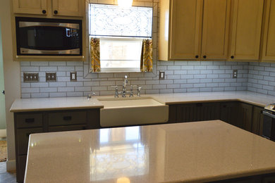 Example of a mid-sized transitional l-shaped porcelain tile enclosed kitchen design in Albuquerque with a farmhouse sink, beaded inset cabinets, yellow cabinets, quartz countertops, white backsplash, subway tile backsplash, stainless steel appliances and an island