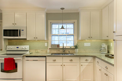 Example of a transitional l-shaped eat-in kitchen design in Other with an undermount sink, shaker cabinets, white cabinets, granite countertops, green backsplash, glass tile backsplash and white appliances