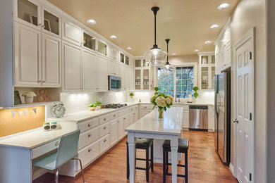 Mid-sized elegant u-shaped medium tone wood floor open concept kitchen photo in Other with an undermount sink, raised-panel cabinets, white cabinets, quartz countertops, white backsplash, subway tile backsplash, stainless steel appliances and an island