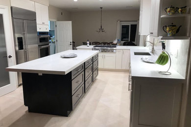 Large trendy u-shaped eat-in kitchen photo in Orange County with a drop-in sink, shaker cabinets, white cabinets, quartzite countertops, white backsplash, stainless steel appliances, an island and white countertops