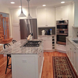 Mid-sized transitional eat-in kitchen designs - Example of a mid-sized transitional l-shaped medium tone wood floor and brown floor eat-in kitchen design in New York with an undermount sink, shaker cabinets, white cabinets, granite countertops, gray backsplash, glass tile backsplash, stainless steel appliances, an island and multicolored countertops