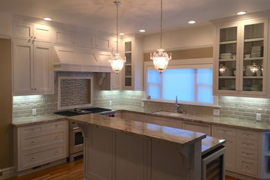 Example of a large arts and crafts u-shaped medium tone wood floor eat-in kitchen design in Sacramento with an undermount sink, shaker cabinets, white cabinets, granite countertops, white backsplash, ceramic backsplash, stainless steel appliances and an island