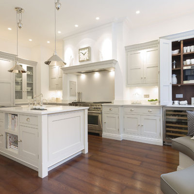 Inspiration for a large transitional l-shaped dark wood floor and brown floor eat-in kitchen remodel in London with shaker cabinets, white cabinets, white backsplash, stainless steel appliances and an island