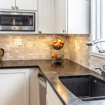 Eat-in kitchen - mid-sized craftsman u-shaped light wood floor eat-in kitchen idea in Burlington with an undermount sink, shaker cabinets, white cabinets, soapstone countertops, white backsplash, stone tile backsplash, stainless steel appliances and an island