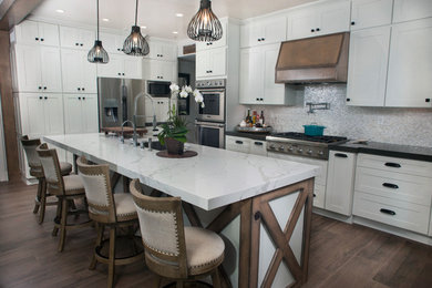 Inspiration for a large cottage l-shaped medium tone wood floor and brown floor eat-in kitchen remodel in Orange County with an undermount sink, shaker cabinets, white cabinets, quartz countertops, white backsplash, glass tile backsplash, stainless steel appliances, an island and white countertops