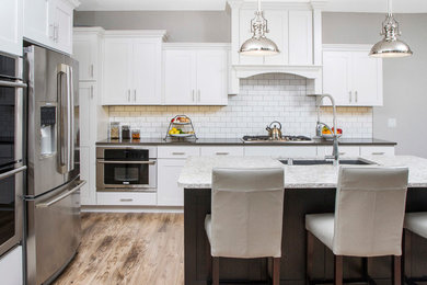 Eat-in kitchen - large craftsman l-shaped light wood floor eat-in kitchen idea in Other with an undermount sink, shaker cabinets, white cabinets, quartz countertops, white backsplash, cement tile backsplash, stainless steel appliances and an island